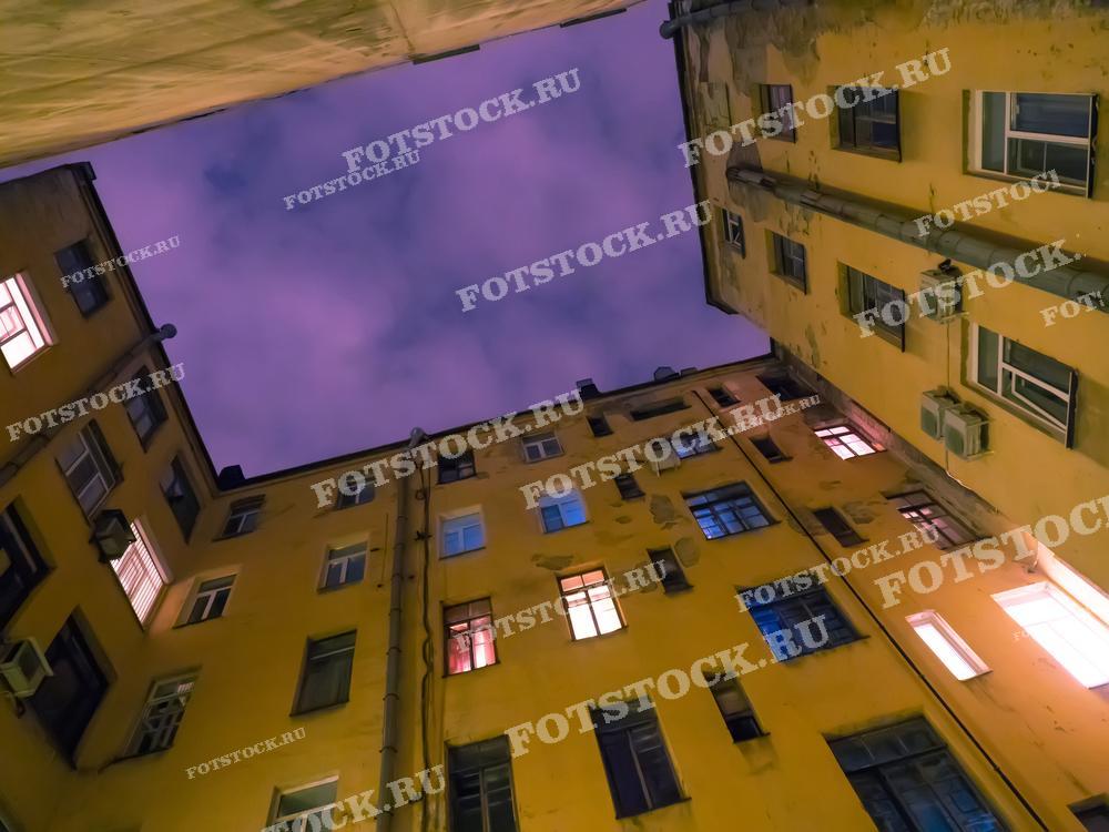 Эта фотография создаёт ощущение уединённого пространства внутри городского двора, где стены домов окрашены в тёплые тона от света окон. Взгляд поднимается вверх к ночному небу, создавая чувство масштаба и интимности внутри городской архитектуры. Это изображение может быть использовано для иллюстрации жизни в городе, особенно в контексте живописного Санкт-Петербурга, в качестве обложки книги или альбома, а также как часть урбанистической фотографической коллекции.